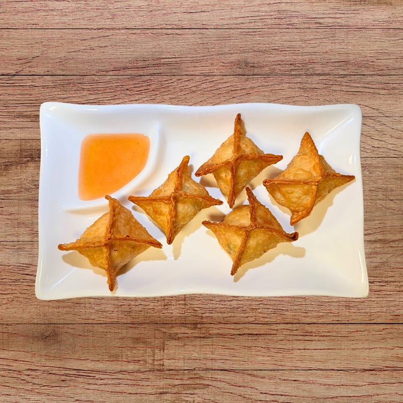 Five golden-brown crab rangoons and a small dish of orange dipping sauce on a white rectangular plate.