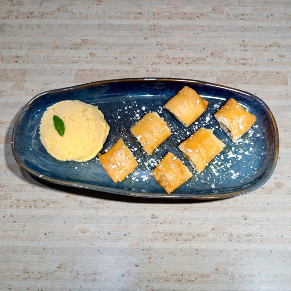 A blue platter with a scoop of yellow ice cream and six powdered sugar pastries.