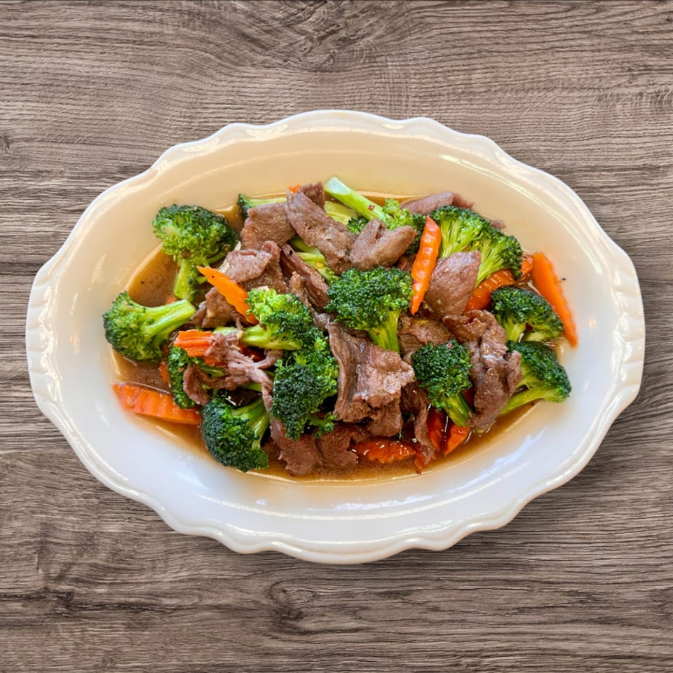 Kwan Thai Cuisine's beef and broccoli stir-fry with carrots in a savory sauce on a white plate.